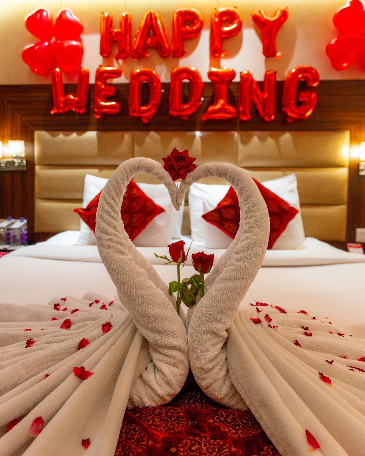 A room dressed for a wedding night, towel swans and rose petals