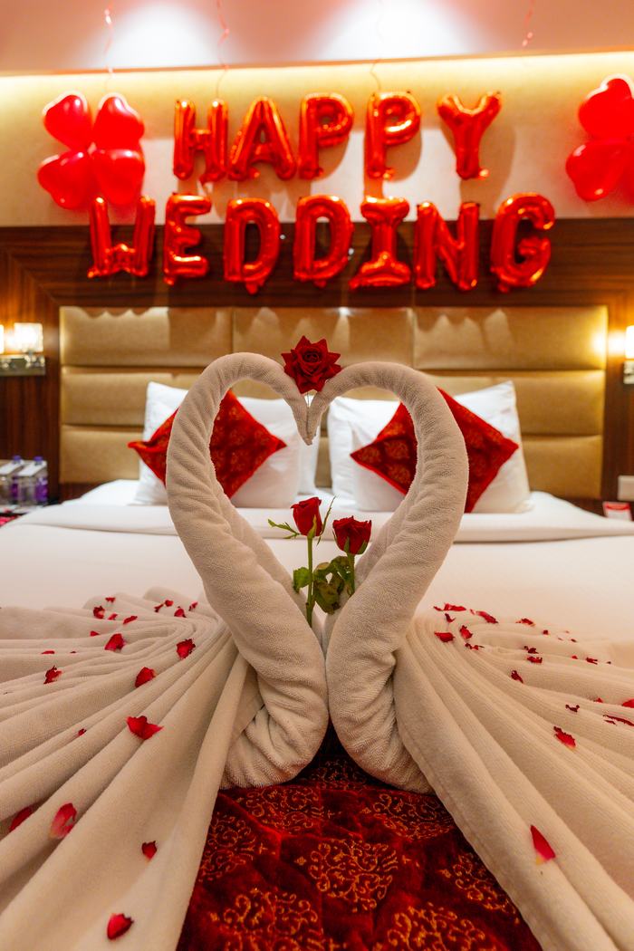 A room dressed for a wedding night, towel swans and rose petals